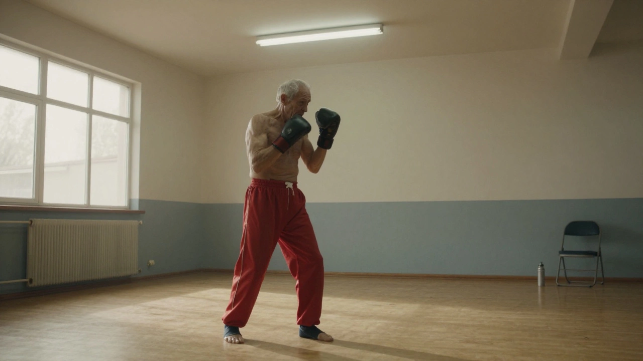 An elderly man shadowboxing alone in a quiet community center, wearing faded red trunks.